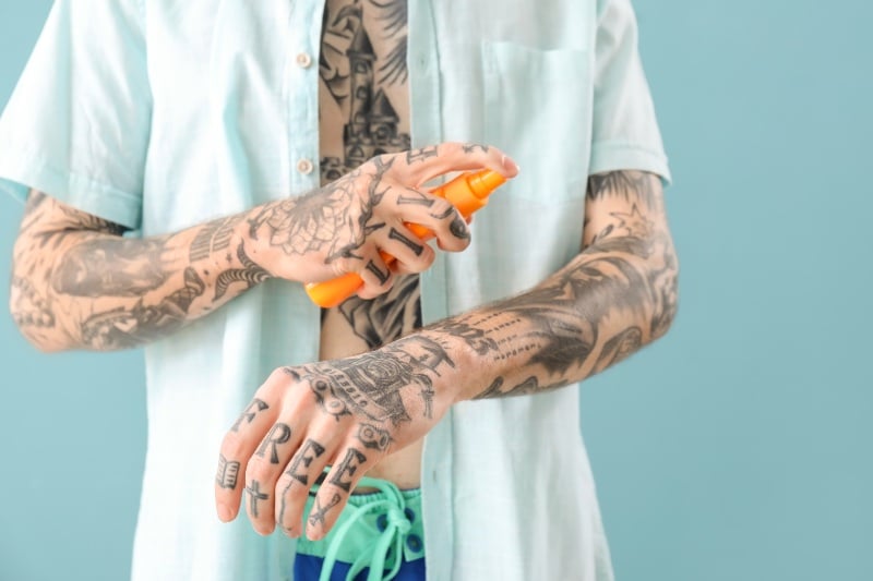 A man puts on sunscreen to protect his tattoos from the sun