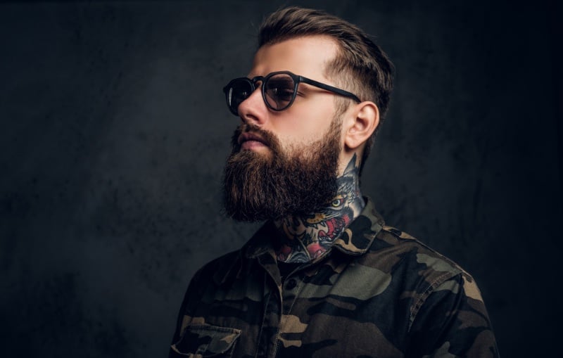 Man wearing glasses with side neck tattoo posing for photo