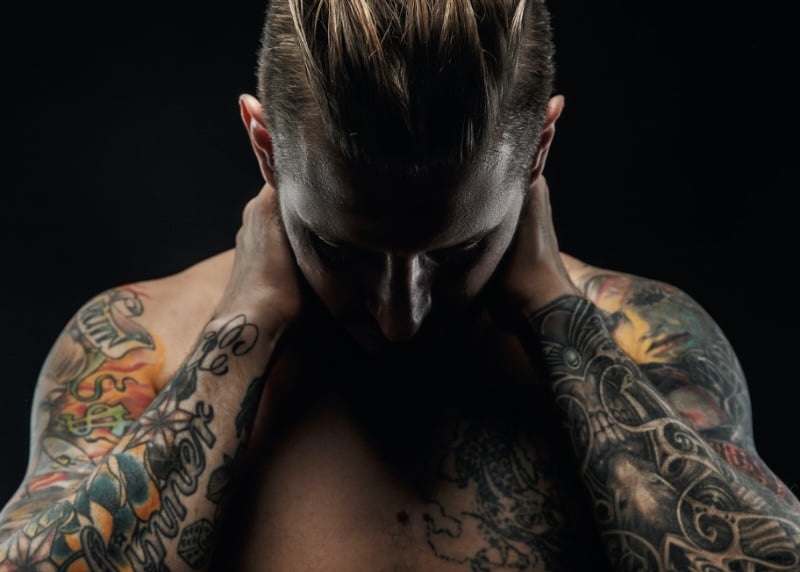 Man with tattoos posing with black background