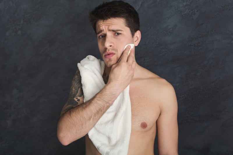 Man with an arm tattoo drying his face with a towel