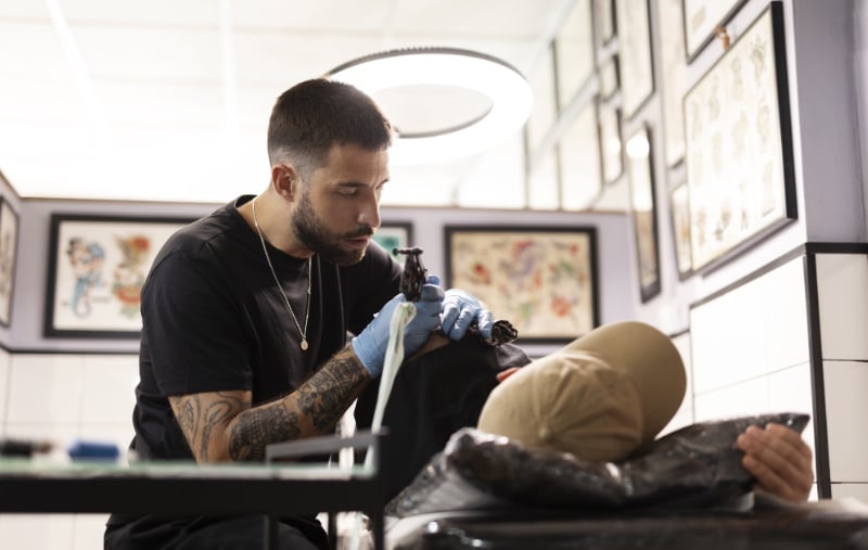 tattoo artist doing a shoulder tattoo